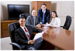 four employees of different nationalities sitting at conference room table